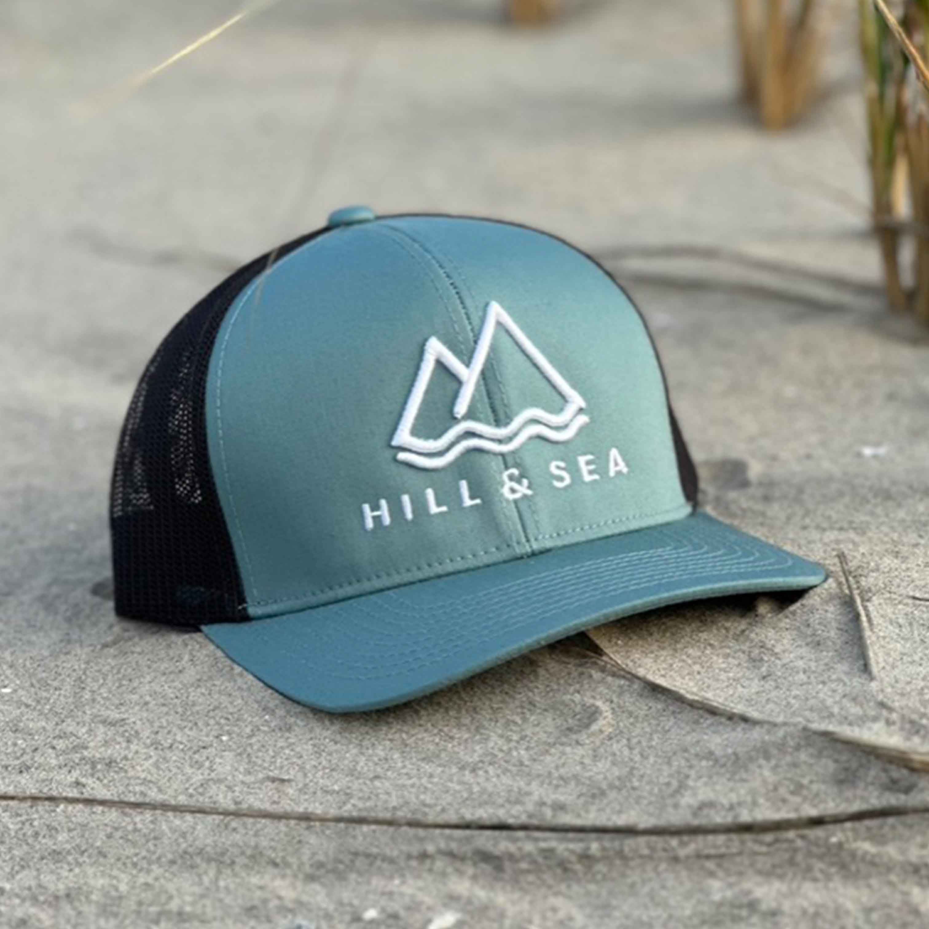 Smoke blue/charcoal trucker snapback cap in the sand